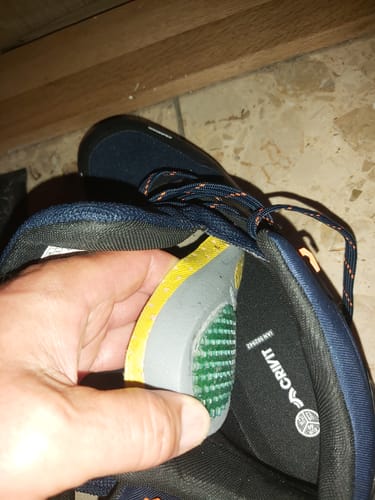 Reviewer's hand inserting the Ortopéd Pro Talpbetét orthotic insert into a dark blue sneaker.
