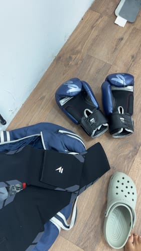 Reviewer's Maintien de compression V2 sur un sol en bois à côté de gants de boxe bleus et d'une chaussure claire.