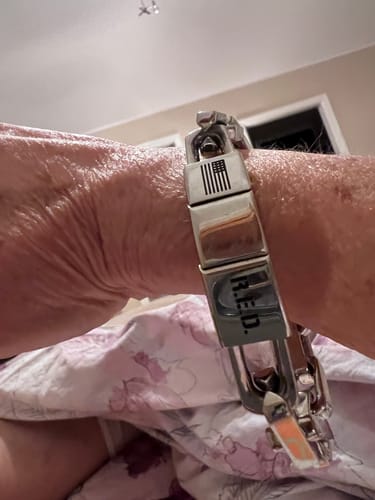 Reviewer's wrist wearing the R.E.D. Remember Everyone Deployed Silver Bracelet, showing the engraved text and flag.
