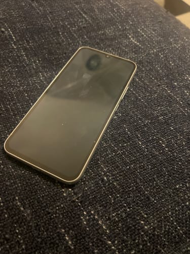 Customer's Samsung Galaxy A34 5G showing the front display screen resting on a dark fabric surface.