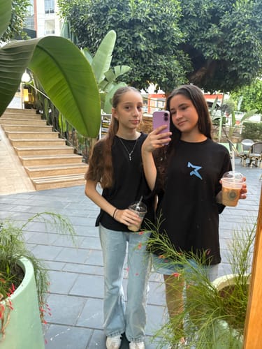 Customer's Idol House Grand Final Merch siyah t-shirt on a person, capturing a mirror selfie in an outdoor setting.