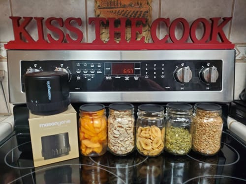 Customer's Mason Genie Vacuum Sealer Kit with five sealed glass jars of food sitting on a stovetop.