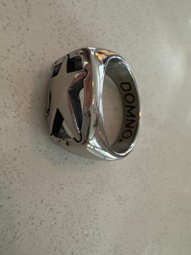 Reviewer's silver Shooting Star ring featuring a star cutout design, resting on a textured surface.