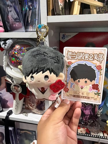 Reviewer's hand holding a Mori plush keychain from Ouran High School Host Club with its character card.