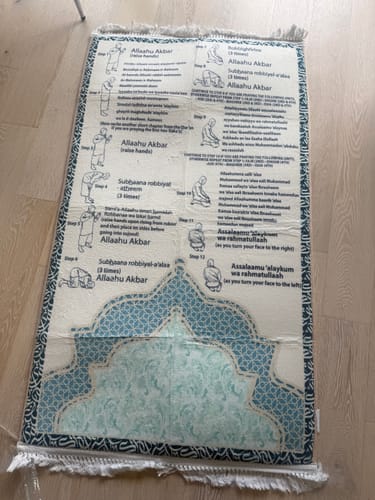 Customer's Step-by-Step Phonetic Salah Padded Prayer Mat laid flat on a light wood floor.