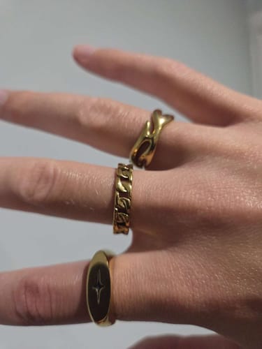 Customer's hand wearing three gold-toned Starlight Rings, including one with a star design.