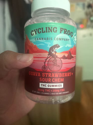 Customer's hand holding a jar of Guava Strawberry Rosin Gummies with a cycling frog illustration on the label.