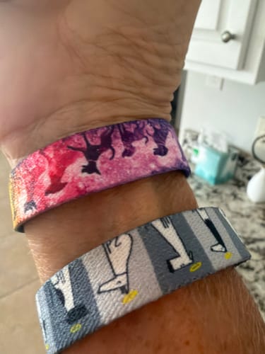 Customer's wrist wearing two colorful Dog Pack bracelets with dog-themed patterns.