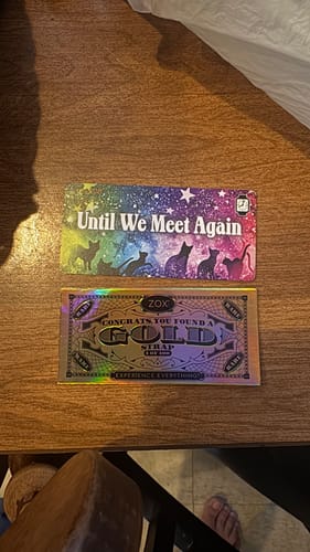 Customer's Until we meet again Cat Watchband display card and a gold Zox strap card on a wooden surface.