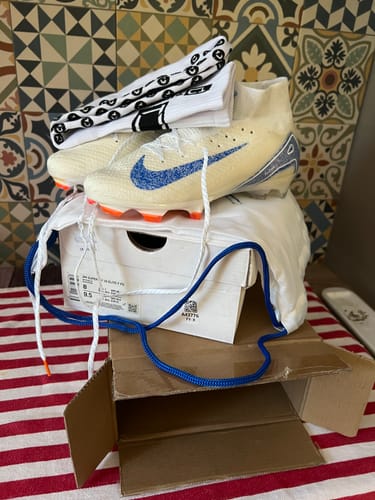 Customer's Mercurial Superfly 10 Elite FG shoes with white and blue design, including socks and a bag, on a table.
