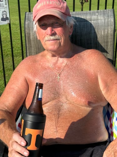Customer's Universal Buddy can cooler with a Tennessee Vols design holding a bottle outdoors.