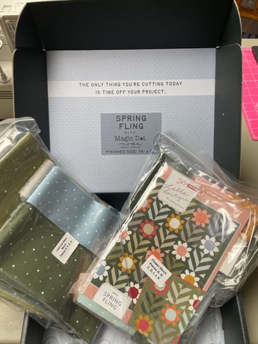 Reviewer's Spring Fling quilt kit, showing packaged fabric bundles and instructions inside the open project box.