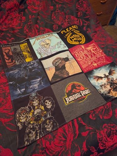 Customer's Project Repat T-Shirt Quilt featuring various colorful music and movie graphics laid on a patterned bed.