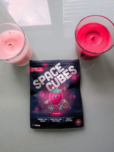 Customer's LEAFZ THC Space Cubes Himbeere packaging on a table between two lit candles.