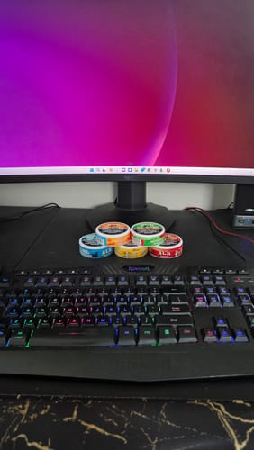 Customer's five Drifters Combo Pack tins stacked on a desk in front of a computer keyboard and monitor.