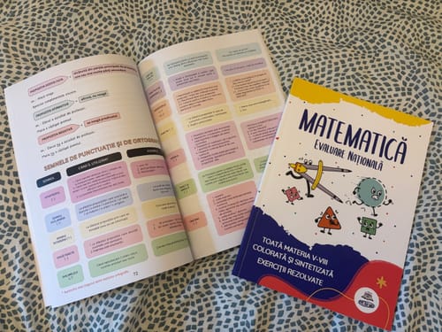 Reviewer's Bacademia Evaluare Națională study books open to colorful tables and a closed Mathematics study guide.
