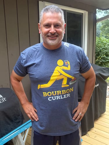 Customer's Bourbon Curler Athlete T-Shirt, a blue shirt featuring a yellow graphic of a person curling with a glass.