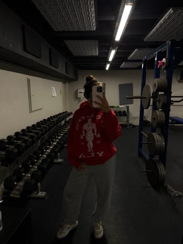 Reviewer in a gym mirror selfie wearing a red Golds Gym Classic Pullover and grey sweatpants.