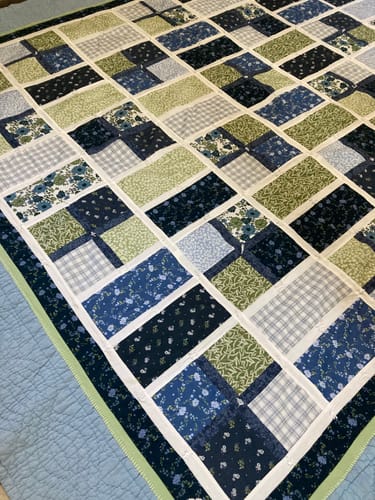 Customer's Apple Cider Quilt Kit featuring a patchwork pattern of blue and green fabric squares.