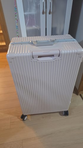 Customer's beige Check-In All-In-One suitcase standing upright on a wooden floor.