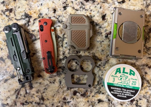 Customer's white and green Tropical Fruit Nicotine Pouches tin displayed on a granite countertop with EDC tools.