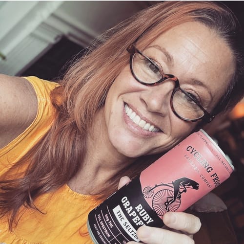 Customer's smiling face holding a can of Ruby Grapefruit THC Seltzer