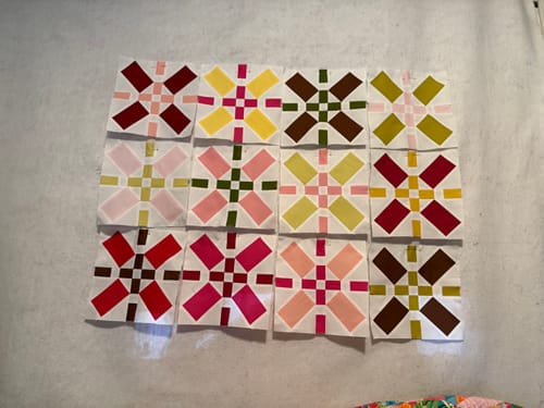 Reviewer's twelve colorful X-shaped quilt blocks laid out in a grid for the Positive Vibes Quilt Kit.