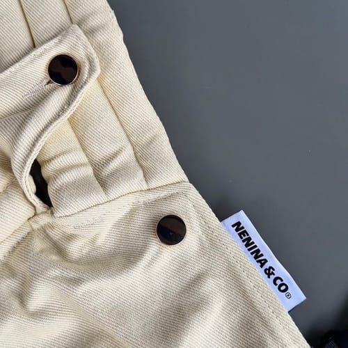 Customer's beige HUG ergonomic carrier showing fabric detail, structural buttons, and Nenina & Co brand label