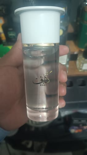 Mano de un cliente sosteniendo el frasco de perfume Ahmed al Maghribi KAAF, mostrando su diseño transparente.