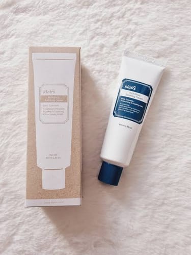 Customer's Rich Moist Soothing Cream packaging box next to the white cream tube on a soft textured surface.