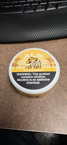 Customer's yellow Drifters Island Peach nicotine pouch container resting on a desk.