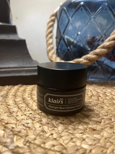 Customer's Klairs Midnight Blue Calming Cream jar sitting on a woven surface in front of a blue glass decorative item.