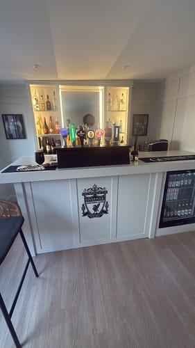 Customer's framed The Good Stuff art print displayed on a wall in a home bar setting.