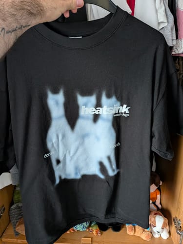 Customer's black Heatsink Watch Dogs tee with a blurred triple-dog graphic print held up by a hand