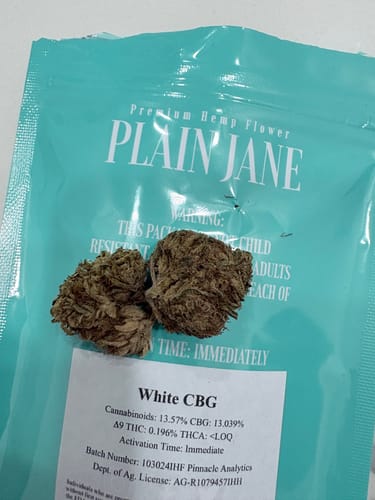 Customer's White CBG hemp flower buds placed on the product packaging showing labeling and cannabinoid details.