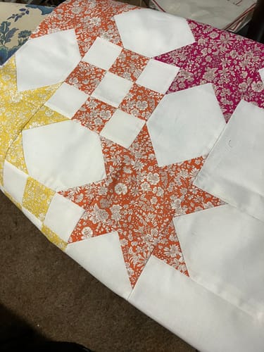 Customer's Star Studded Quilt Kit work in progress, showing colorful floral fabric pieces stitched into star patterns