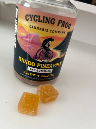 Customer's Mango-Pineapple Gummies bottle, with two orange, sugar-coated, square gummies placed in the foreground.