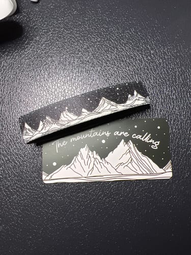 Customer's The Mountains Are Calling bracelet and matching product card with a sketch of mountain peaks.