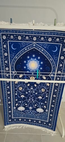 Reviewer's blue Celestial Bloom Padded Prayer Mat hanging on a drying rack.