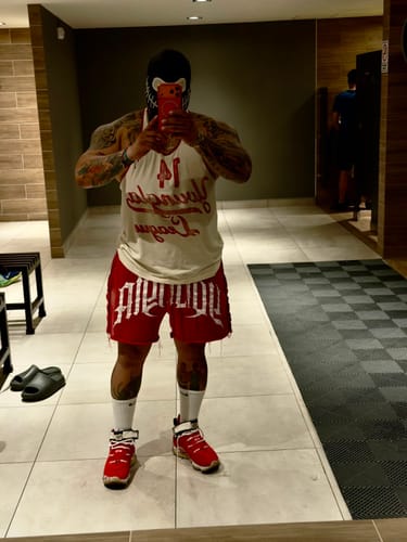 Customer's Golden Era League Stringer and red shorts worn in a gym mirror selfie.