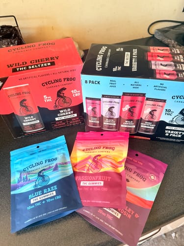 Customer's collection of Cycling Frog variety packs and THC gummy bags on a table.