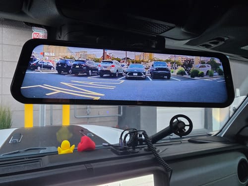 Customer's WOLFBOX G900TriPro rearview mirror dash cam installed and displaying a clear wide-angle view of a parking lot.