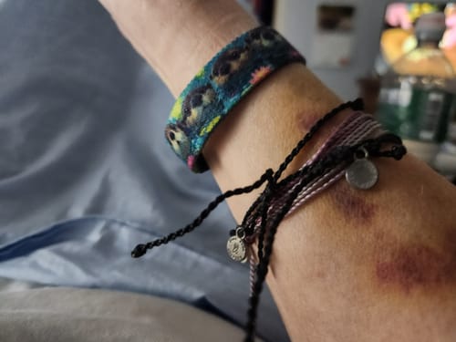 Reviewer's colorful Otterly Adorable Bracelet worn on wrist with other string bracelets