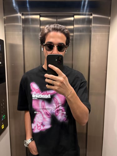Customer's mirror selfie wearing the black Heatsink Pink Noise Tee with a graphic print in an elevator.