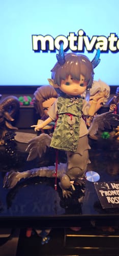 Customer's Penny's Box Adou Meets The Dragon Dream doll with blue horns and a gray dragon-like tail on a dark surface.