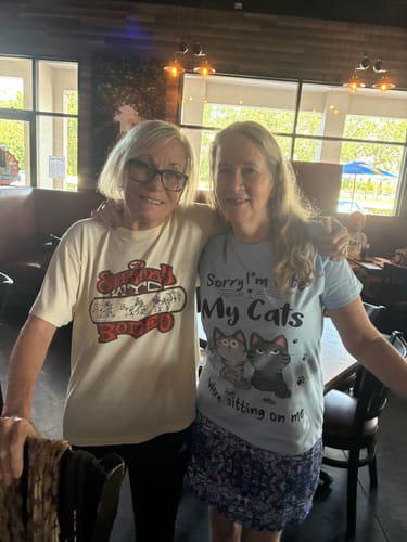 Reviewer wearing a light blue personalized cat shirt featuring cat illustrations and text in a casual setting.
