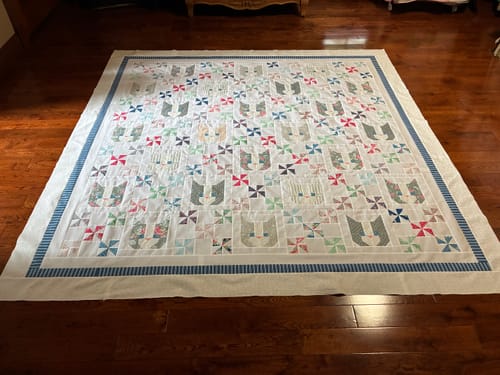 Customer's Star Studded quilt spread flat on a wooden floor, showcasing colorful star patterns and a navy border.