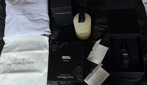Reviewer's Smoke & Mirrors fragrance set featuring the Eau de Parfum bottle, body wash, and branded white dust bags.