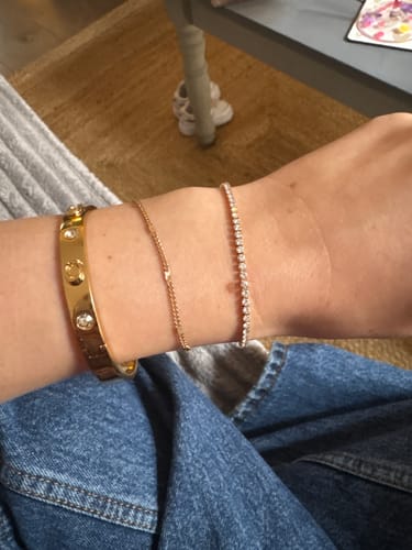 Customer's gold Cordelia Tennis Bracelet worn on their wrist alongside other bracelets.