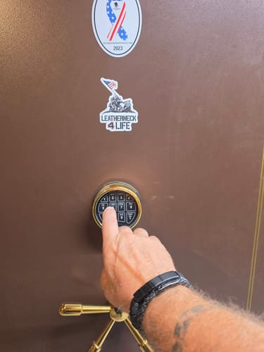 Customer's Morse Code URN leather bracelet on wrist while pressing a safe keypad.